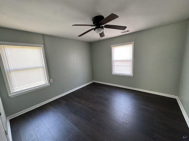 empty room featuring baseboards, visible vents, ceiling fan, and dark wood-type flooring