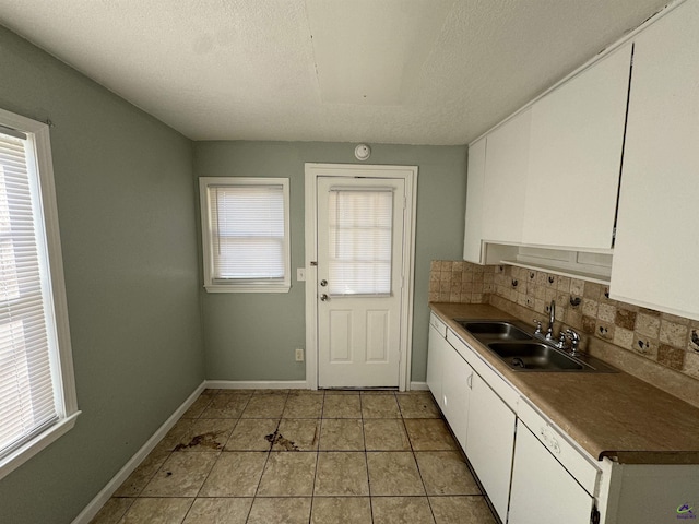 kitchen with a sink, white cabinetry, baseboards, decorative backsplash, and dishwasher