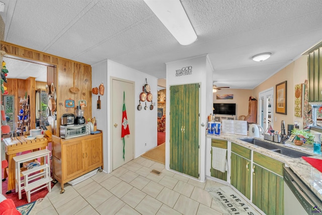 kitchen with a ceiling fan, dishwasher, a textured ceiling, wood walls, and a sink