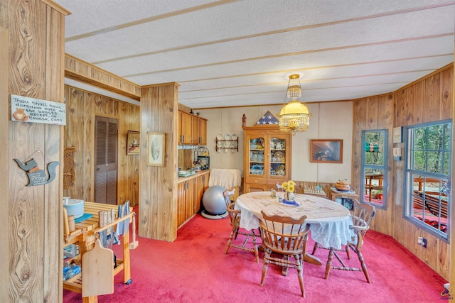 carpeted dining space featuring a textured ceiling and wooden walls