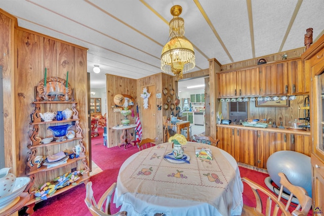 carpeted dining room featuring a chandelier, a textured ceiling, and wooden walls