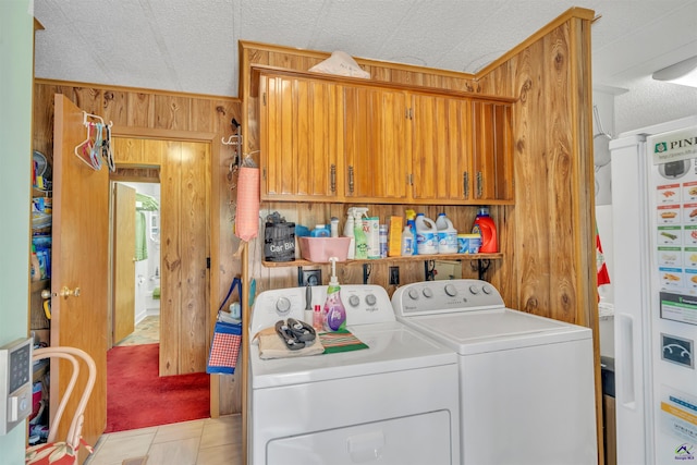 laundry room featuring laundry area, a textured ceiling, wood walls, washing machine and dryer, and water heater