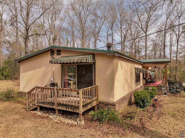 rear view of property with a wooden deck and stucco siding