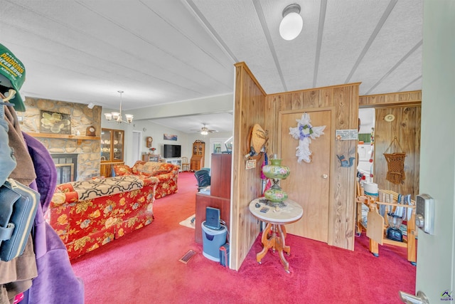 interior space featuring wooden walls, lofted ceiling, a stone fireplace, and a textured ceiling