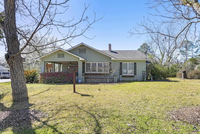 view of front of home with a chimney, a front lawn, and stucco siding