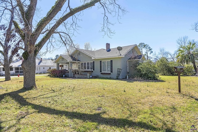 view of front facade with a front lawn, a chimney, and stucco siding