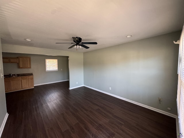 unfurnished living room featuring dark wood-style floors, recessed lighting, a ceiling fan, a sink, and baseboards