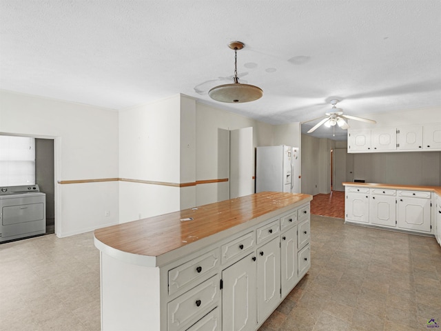 kitchen with white refrigerator with ice dispenser, light floors, washer / clothes dryer, white cabinets, and ceiling fan