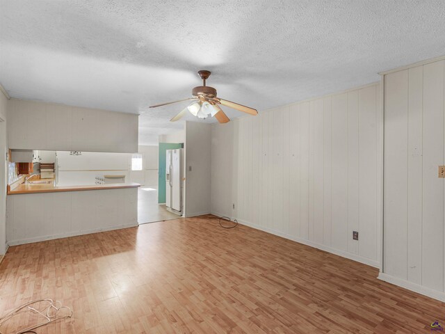 unfurnished living room with a ceiling fan, a textured ceiling, and wood finished floors