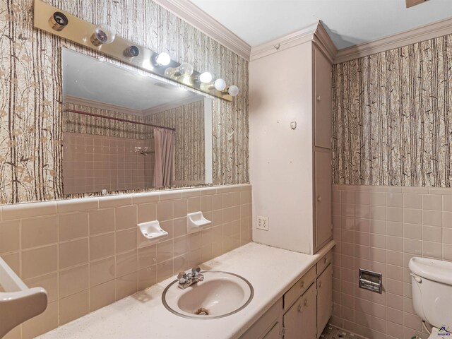 bathroom with wallpapered walls, toilet, a wainscoted wall, ornamental molding, and tile walls