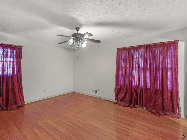 spare room featuring wood finished floors, visible vents, and baseboards