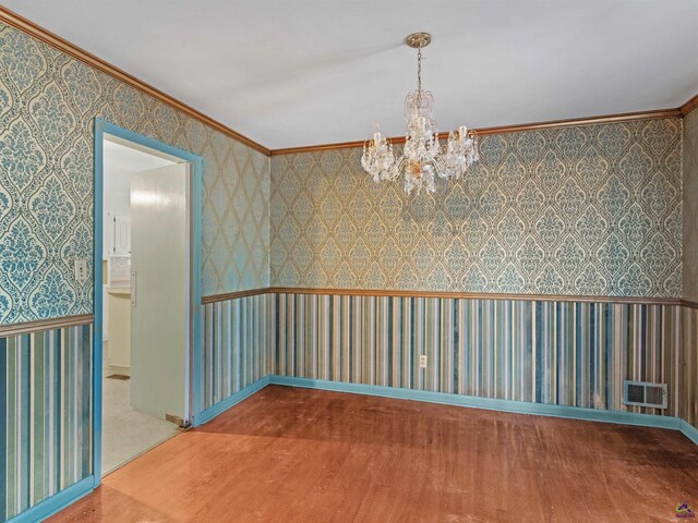 unfurnished room with wallpapered walls, visible vents, ornamental molding, wood finished floors, and a notable chandelier