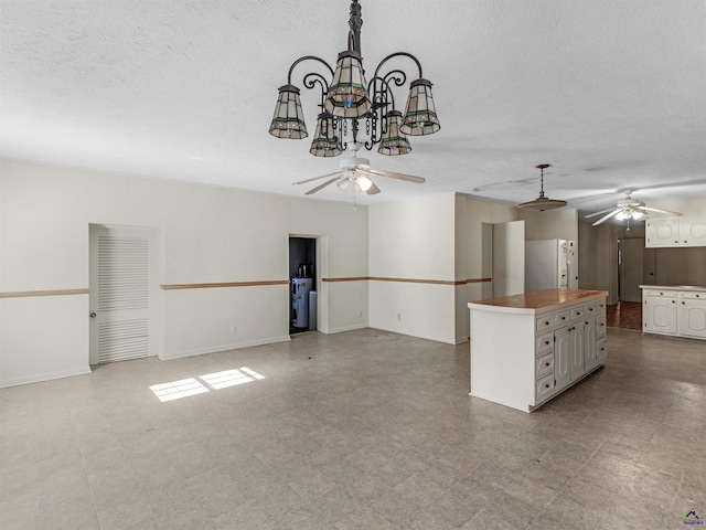 interior space with a center island, white refrigerator with ice dispenser, hanging light fixtures, white cabinets, and tile patterned floors