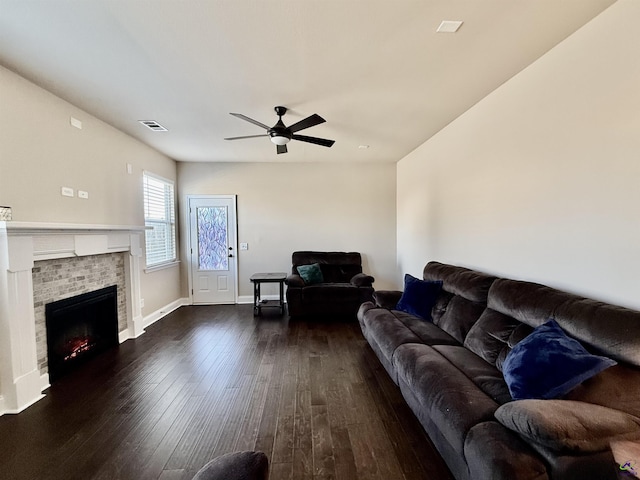 living room with a fireplace, dark wood finished floors, visible vents, ceiling fan, and baseboards