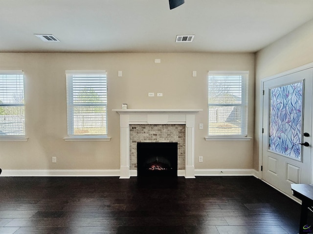 unfurnished living room featuring plenty of natural light, visible vents, and dark wood finished floors