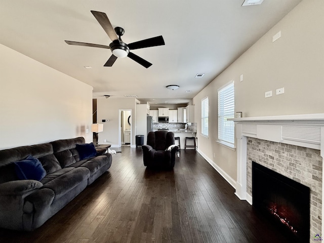 living area with baseboards, visible vents, ceiling fan, dark wood-style flooring, and a fireplace