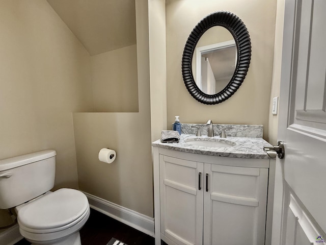 bathroom with vaulted ceiling, vanity, toilet, and baseboards