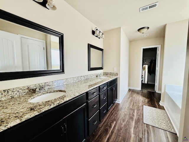 full bathroom featuring double vanity, visible vents, a sink, and wood finished floors