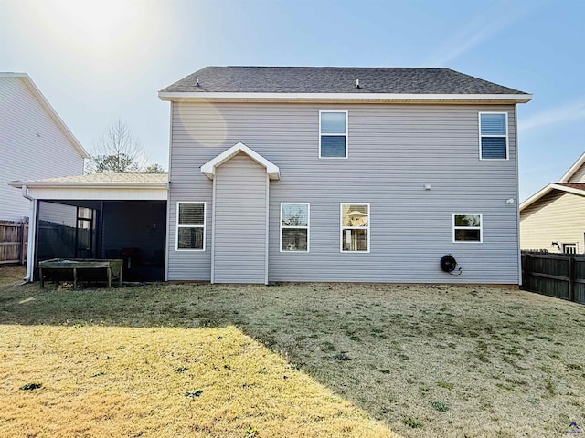 rear view of property featuring a yard, a sunroom, and fence