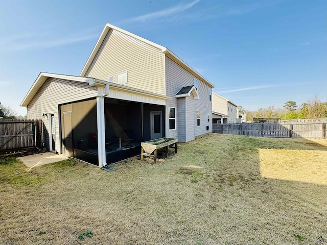 back of house featuring a lawn, a fenced backyard, and a sunroom