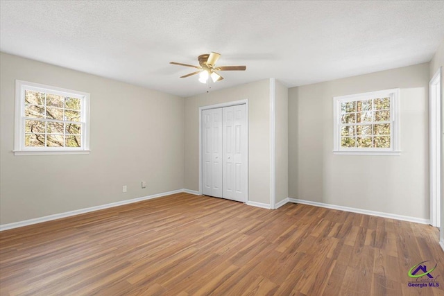 unfurnished bedroom with a closet, multiple windows, and wood finished floors