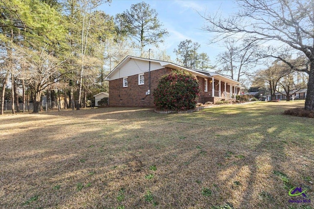 view of side of home with a yard, brick siding, crawl space, and fence