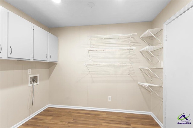 laundry area with washer hookup, cabinet space, and wood finished floors