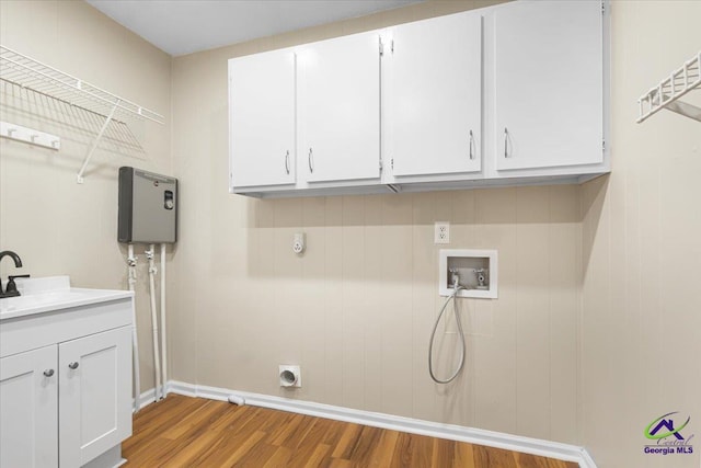 washroom featuring hookup for an electric dryer, washer hookup, wood finished floors, a sink, and cabinet space