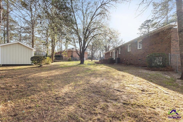 view of yard with fence, central AC, and an outdoor structure