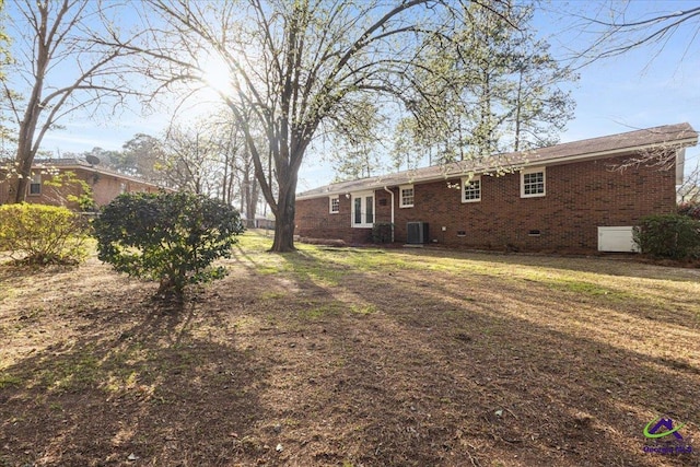 back of property featuring a yard, brick siding, crawl space, and central AC unit