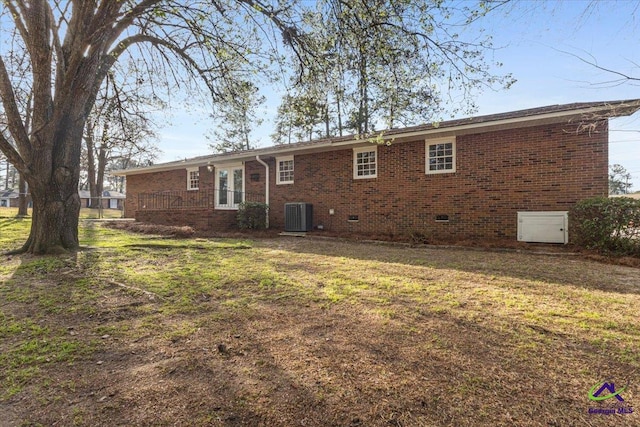 back of house with crawl space, a lawn, cooling unit, and brick siding