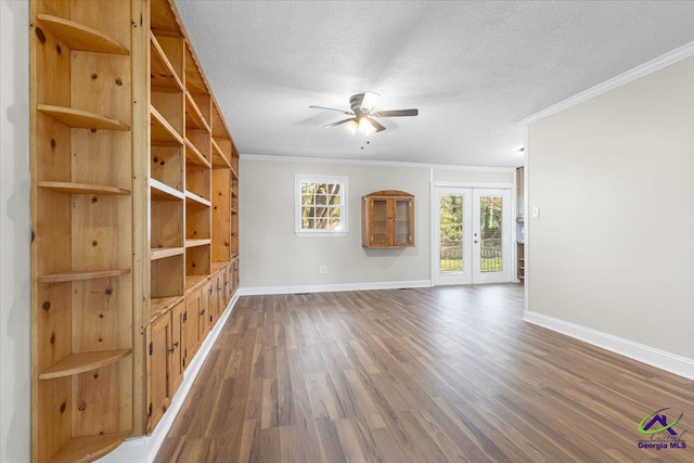 empty room with french doors, dark wood-type flooring, ornamental molding, a textured ceiling, and baseboards