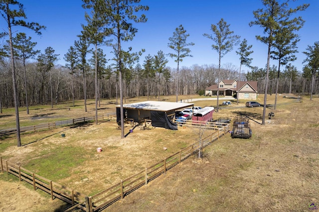 view of yard featuring a forest view, fence, an outbuilding, and a rural view