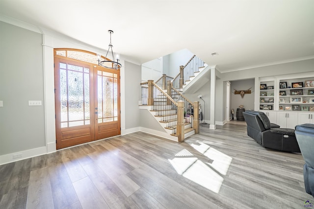 entryway with ornamental molding, baseboards, stairway, and light wood finished floors