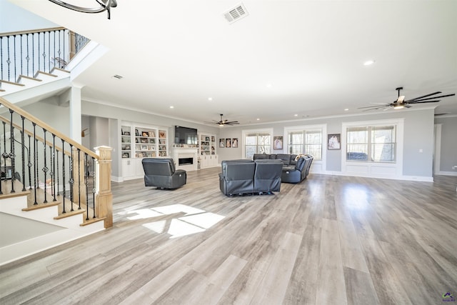 living room featuring visible vents, ornamental molding, wood finished floors, stairs, and a fireplace