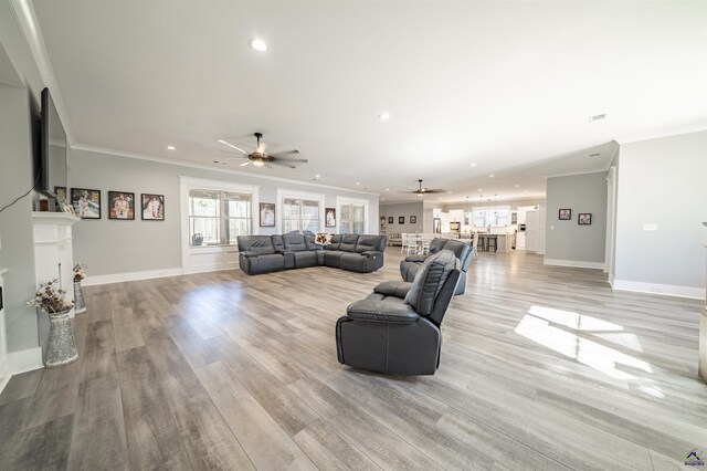 living room with light wood-type flooring, baseboards, ornamental molding, and recessed lighting