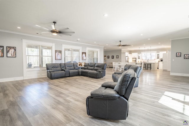 living area featuring baseboards, ceiling fan, ornamental molding, light wood-type flooring, and recessed lighting