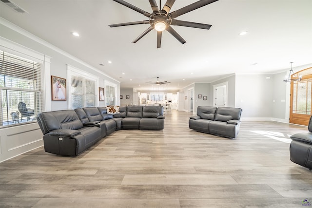 living area featuring light wood-style flooring, visible vents, crown molding, and ceiling fan with notable chandelier