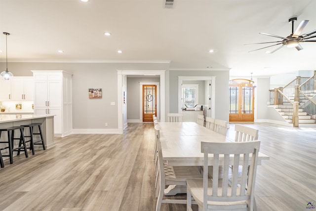 dining area featuring light wood-style flooring, visible vents, baseboards, ornamental molding, and stairway