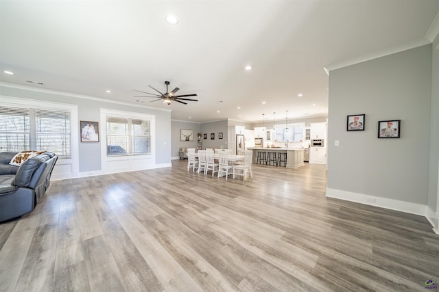 unfurnished living room featuring crown molding, recessed lighting, ceiling fan, light wood-type flooring, and baseboards
