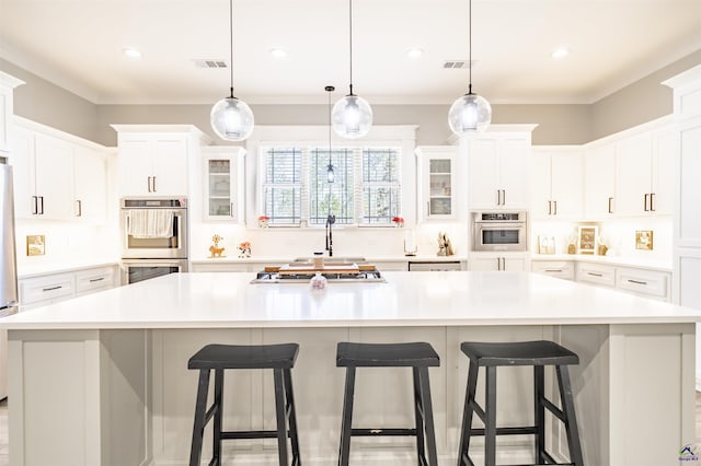 kitchen featuring a large island, visible vents, appliances with stainless steel finishes, glass insert cabinets, and white cabinets