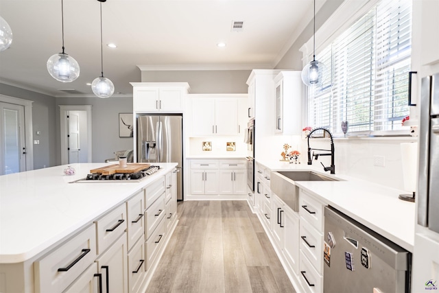 kitchen featuring stainless steel appliances, a sink, visible vents, light countertops, and crown molding
