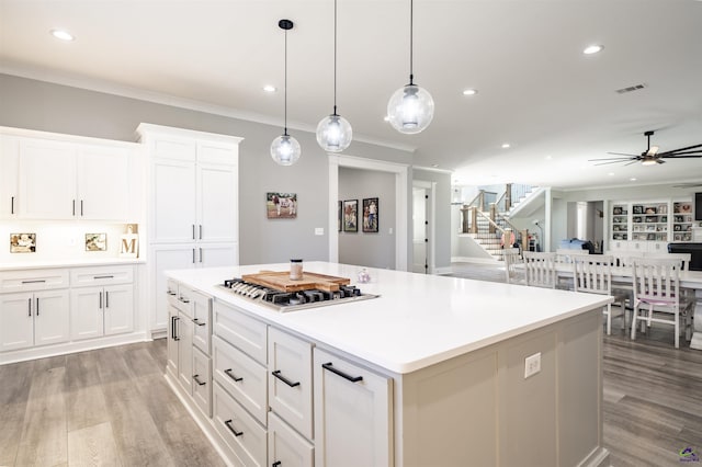 kitchen with crown molding, recessed lighting, a kitchen island, ceiling fan, and light wood-type flooring
