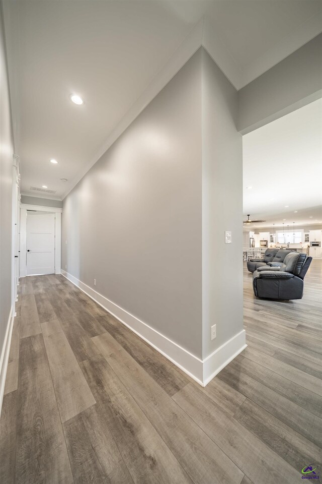 corridor featuring baseboards, wood finished floors, and recessed lighting