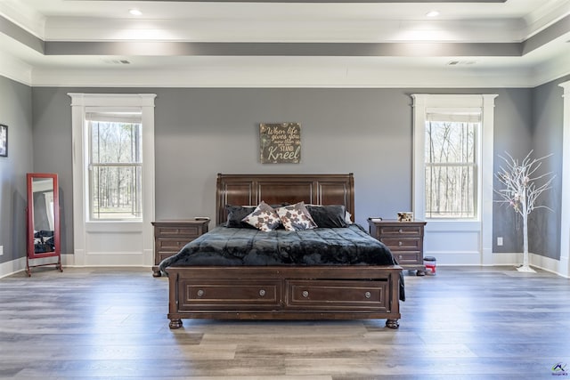 bedroom featuring baseboards, crown molding, a tray ceiling, and wood finished floors