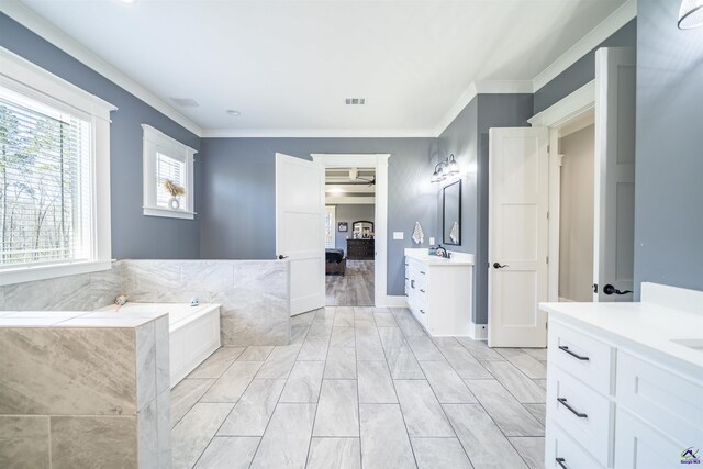 bathroom with visible vents, two vanities, a garden tub, crown molding, and a sink