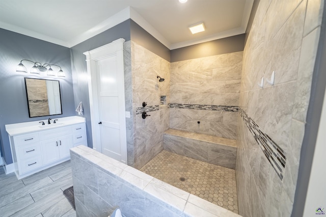 full bathroom featuring ornamental molding, tiled shower, and vanity