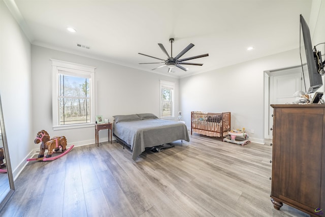 bedroom featuring light wood finished floors, visible vents, baseboards, and ceiling fan
