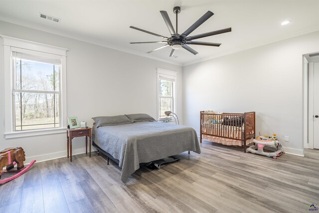 bedroom with visible vents, baseboards, light wood-style flooring, and crown molding
