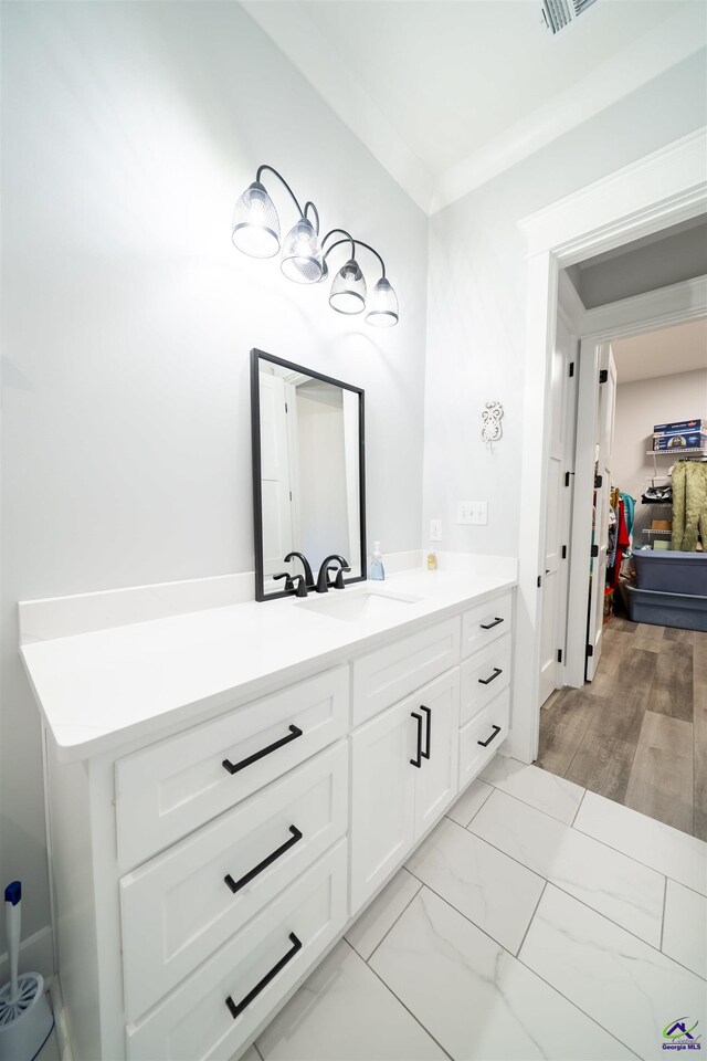 bathroom with marble finish floor, vanity, and crown molding